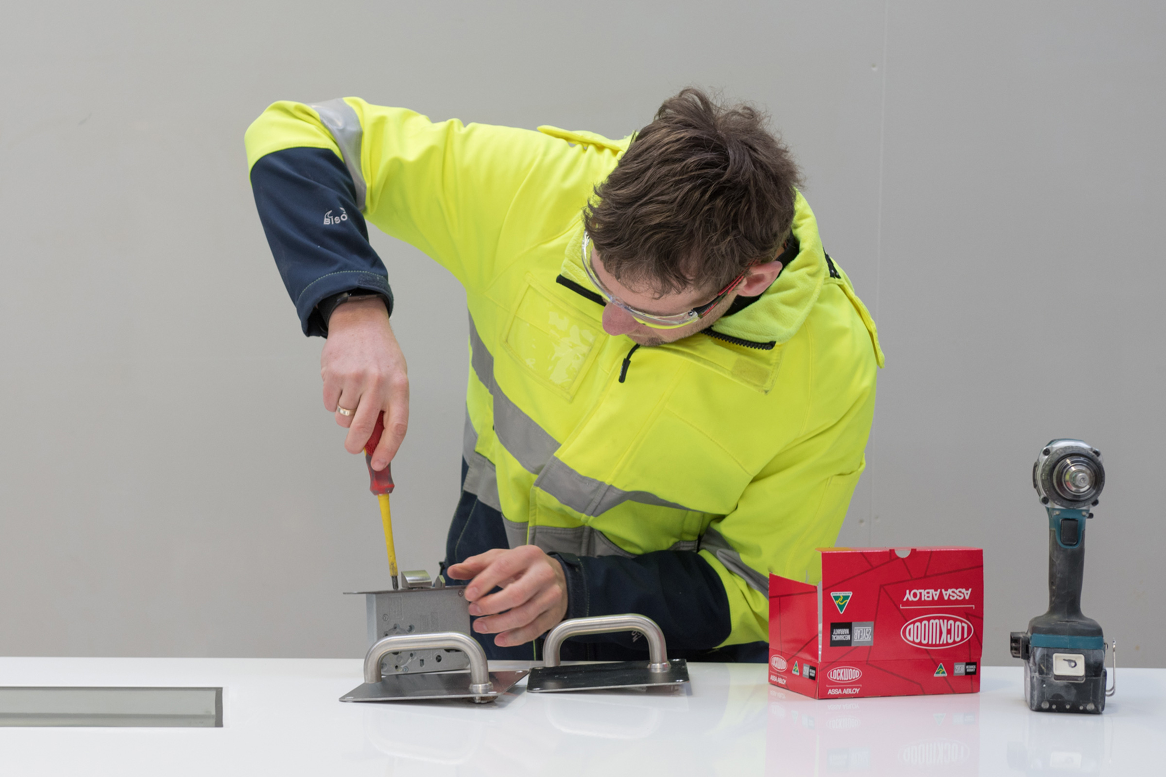 A man in high viz clothing and safety glasses preparing to install Lockwood handles on K2 doors